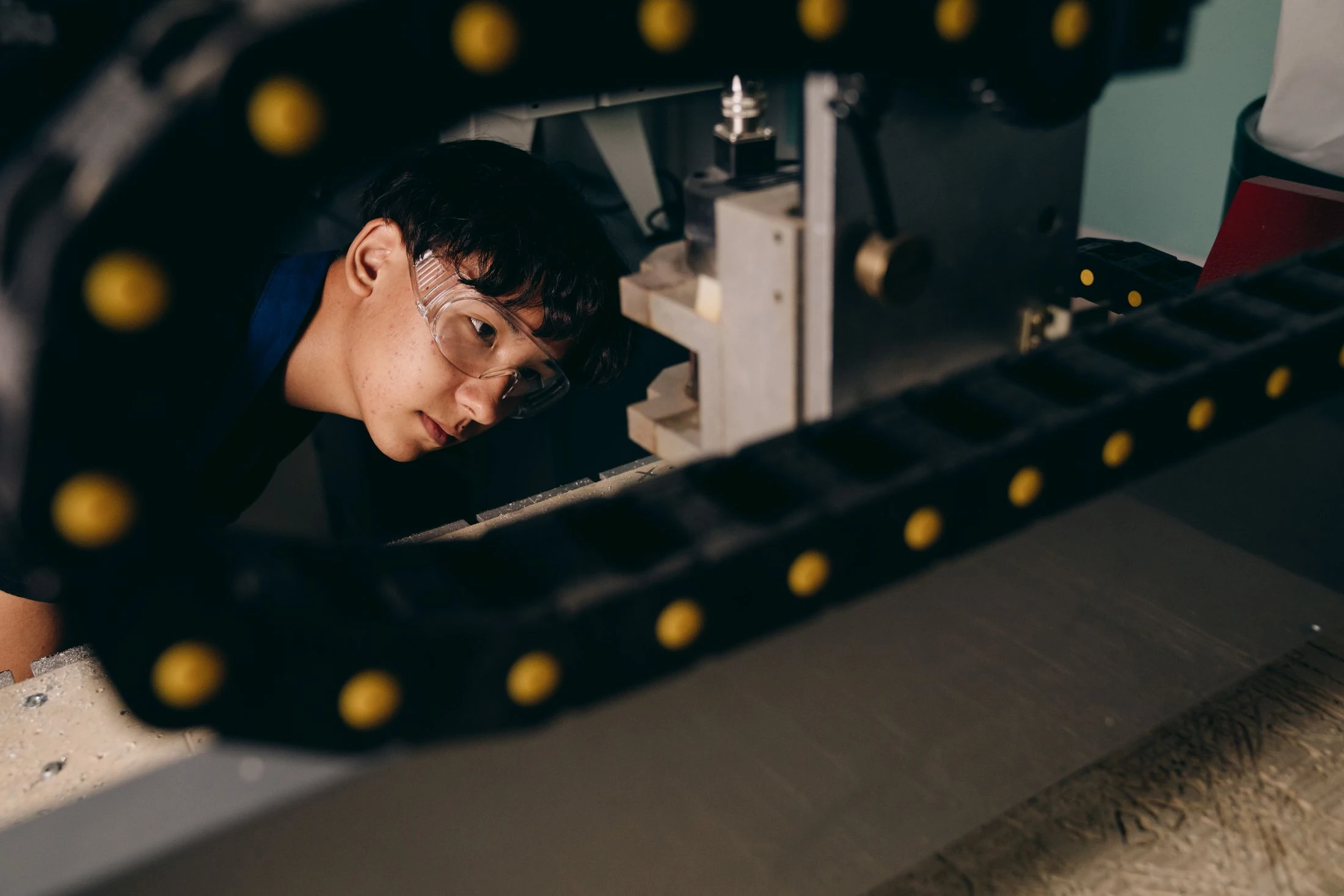 Engineer wearing safety goggles closely checks workshop machinery