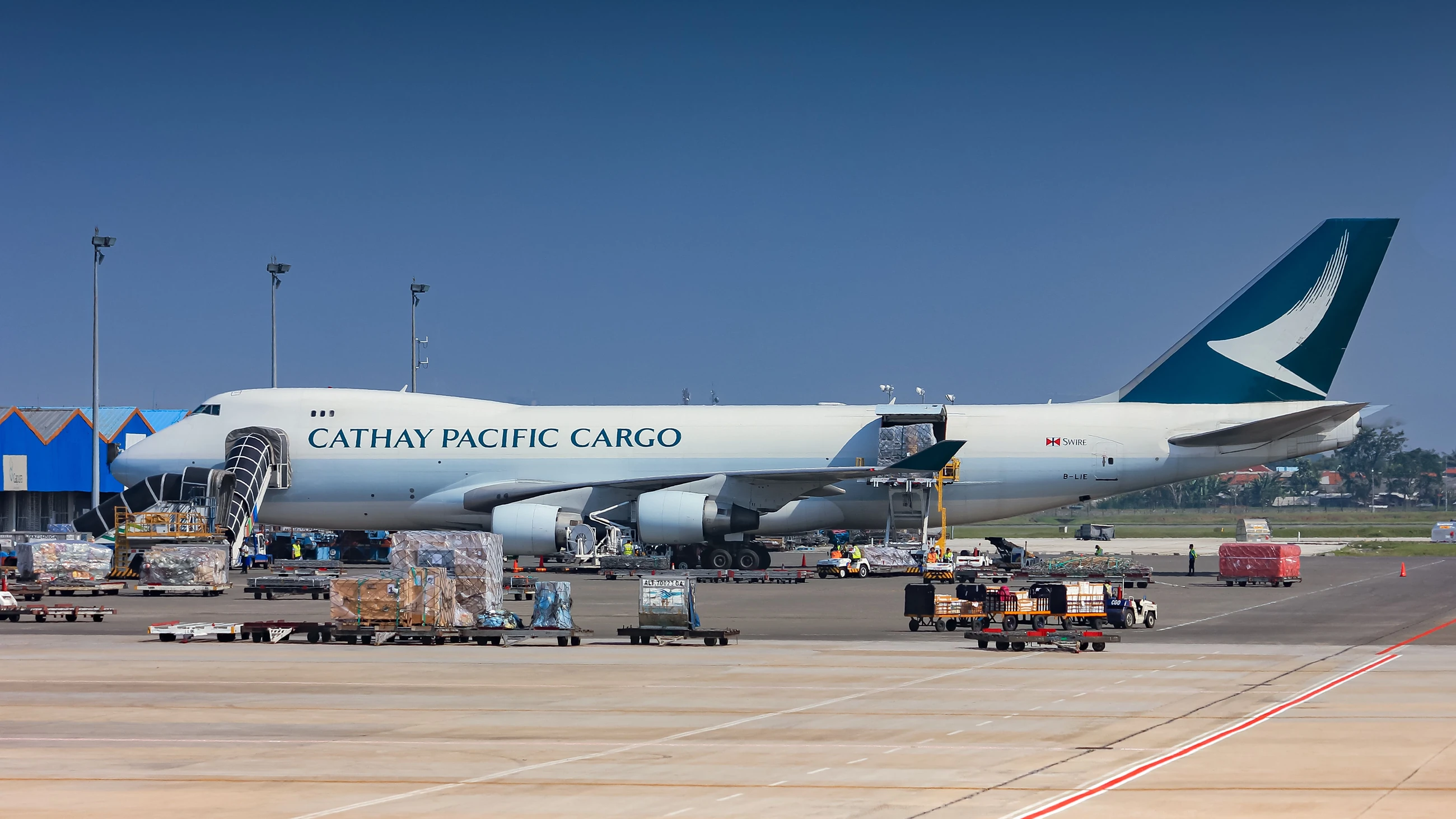 Cathay Pacific cargo aircraft with open cargo doors, freight pallets and ground handling equipment