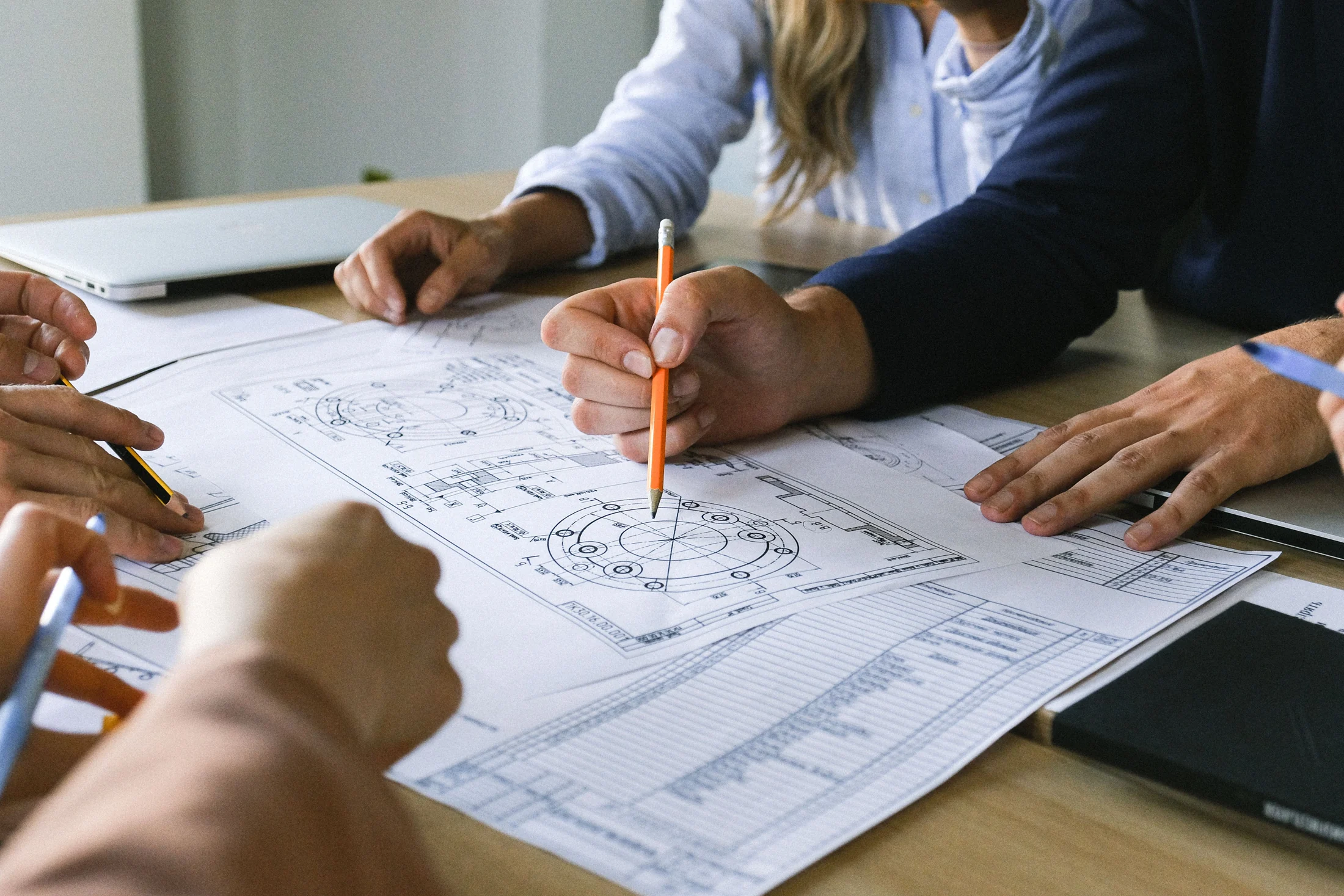 Technical drawings and specifications being reviewed around a project table