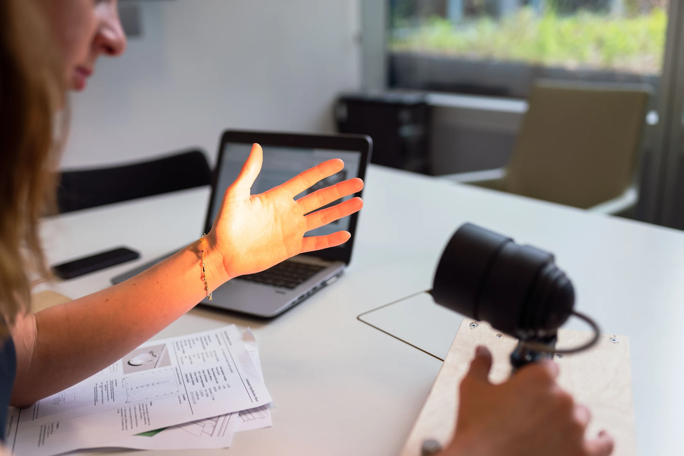 Engineer checking a lighting product alongside its specification sheets and laptop