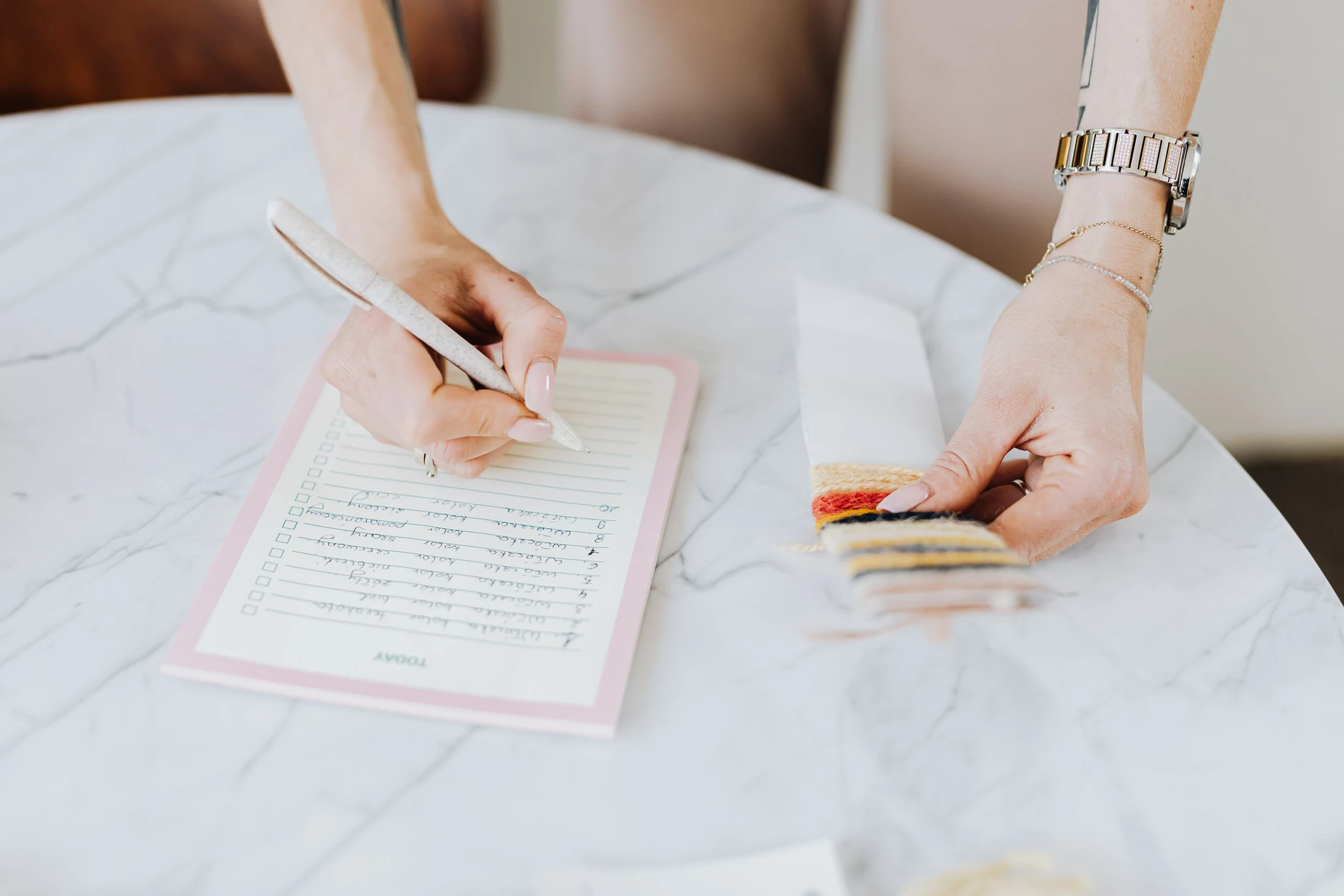Hands reviewing material swatches while writing a checklist