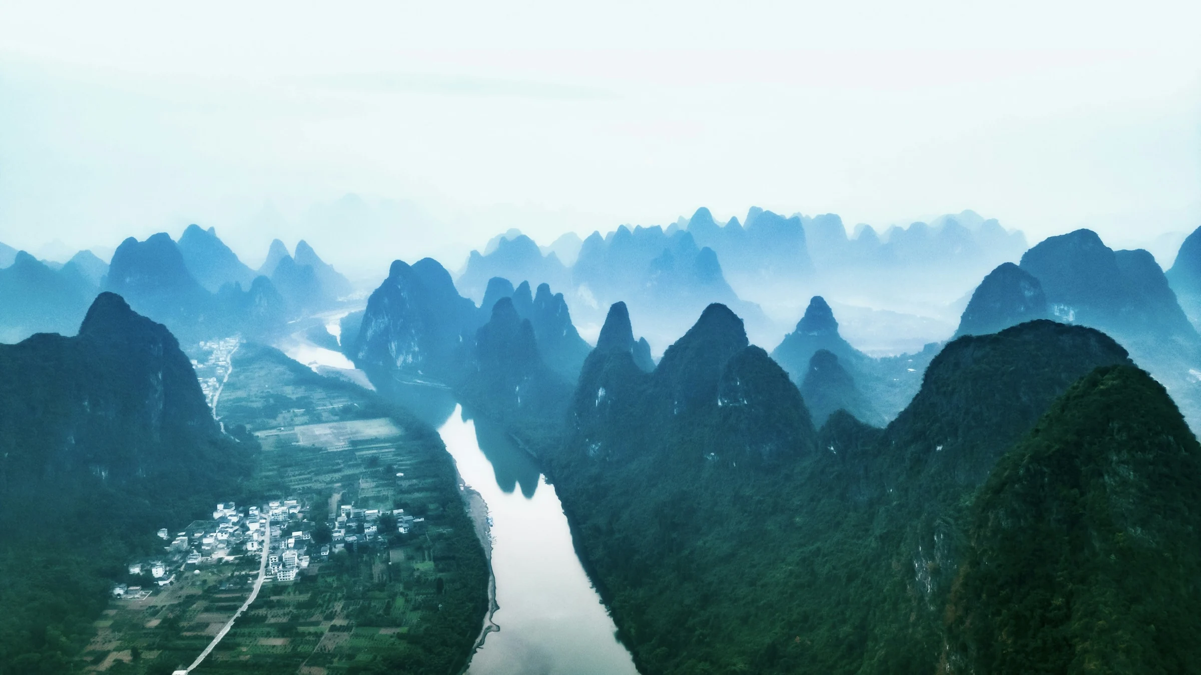 A river winding between forested limestone mountains near Guilin, China