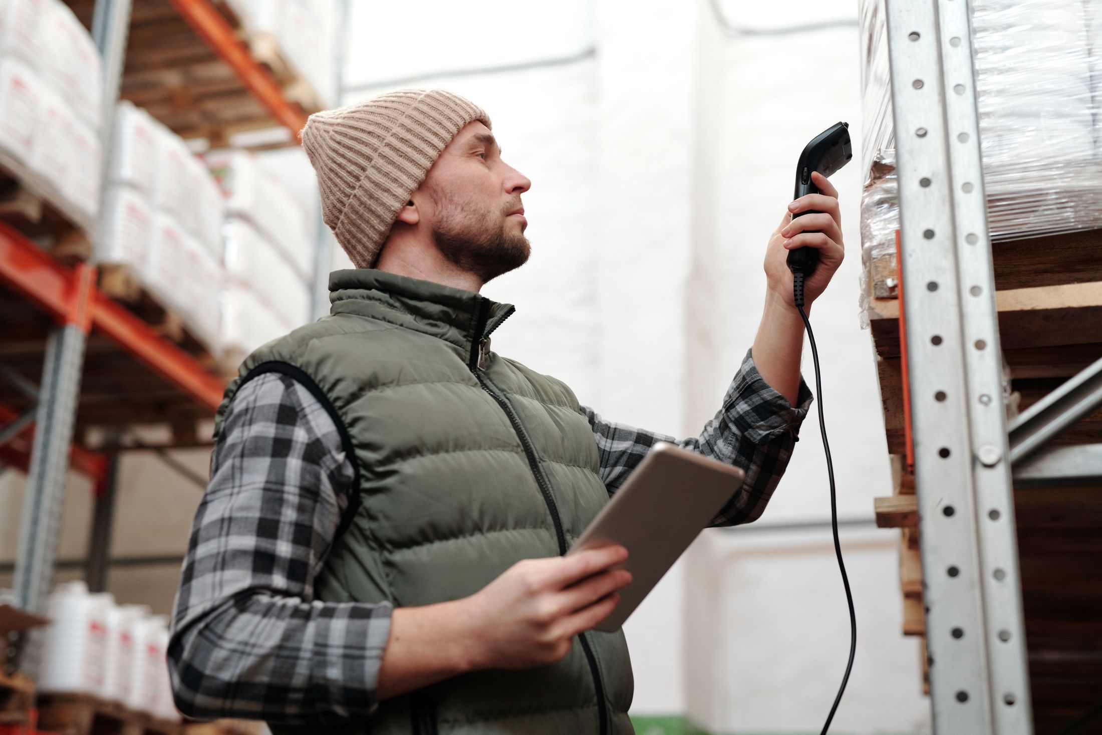 Warehouse worker checking stored goods with a handheld scanner and tablet